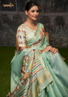 A beautiful seated portrait of the model in a Vanya Sarees green Tussar silk saree, highlighting the artistic Pichwai print.