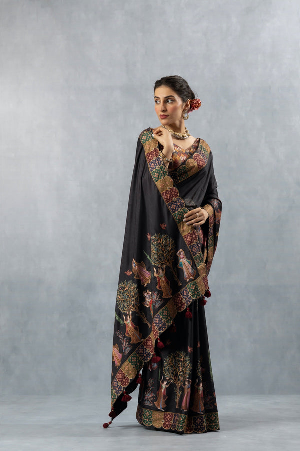 An graceful pose of the model in the Vanya Sarees black folk art saree, highlighting the unique printed border and pallu.