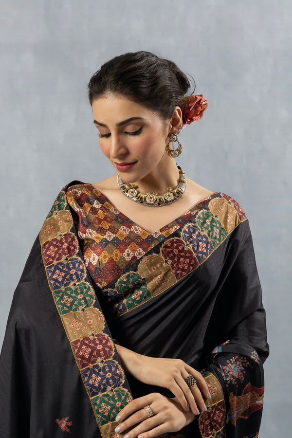 A close-up showing the rich, multi-color Patola-style printed border of the Vanya Sarees black designer saree.