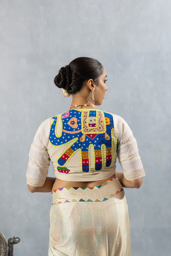 The stunning handcrafted elephant appliqué on the back of the off-white designer blouse from Vanya Sarees.