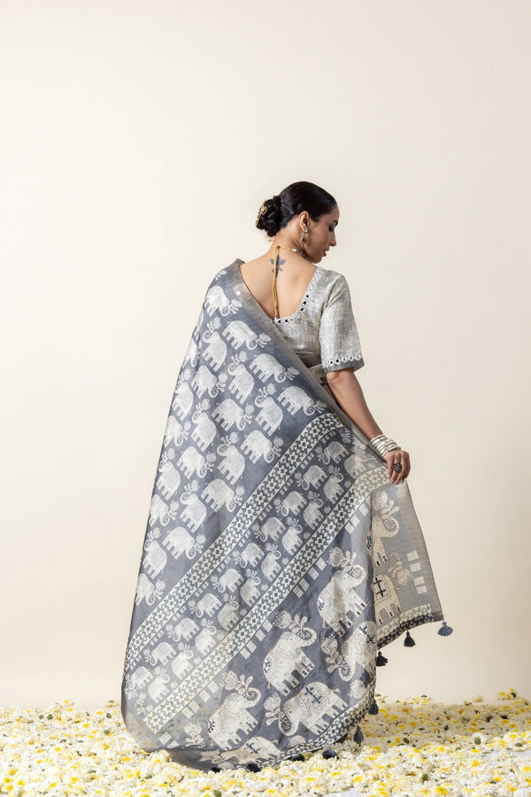A full back view of the model, displaying the extensive elephant print on the pallu of the Vanya Sarees grey Modal silk saree.