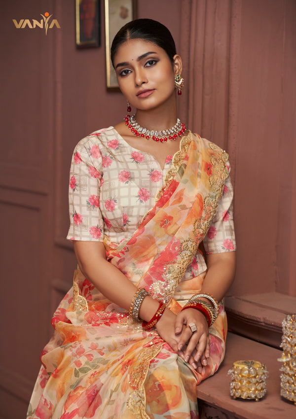 A beautiful seated portrait of the model in a Vanya Sarees organza saree, highlighting the heavy floral embroidery on the border and the printed designer blouse.