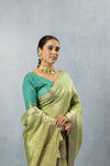 A close-up of the model in a Vanya Sarees green tissue saree, highlighting the rich Banarasi border and contrasting designer blouse.