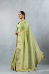 A beautiful side profile of the model wearing the Vanya Sarees green tissue silk saree, showing its shimmering texture and graceful drape.
