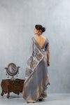 A full back view of the model in the Vanya Sarees ensemble, displaying the drape of the folk art print pallu and the deep V-back of the blouse.