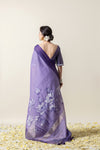 A full back view of the model in the Vanya Sarees ensemble, displaying the lotus print pallu and the dramatic deep V-back of the designer blouse.