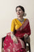 A smiling model seated gracefully in a Vanya Sarees maroon georgette saree, showcasing the hand-embellished yellow designer blouse.