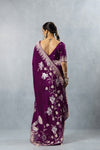 Back view of a model in a Vanya designer saree, displaying the deep V-neck blouse, braided hair, and the beautiful drape of the swan motif pallu.