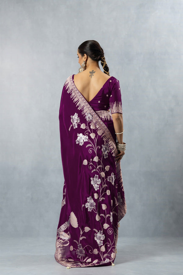 Back view of a model in a Vanya designer saree, displaying the deep V-neck blouse, braided hair, and the beautiful drape of the swan motif pallu.