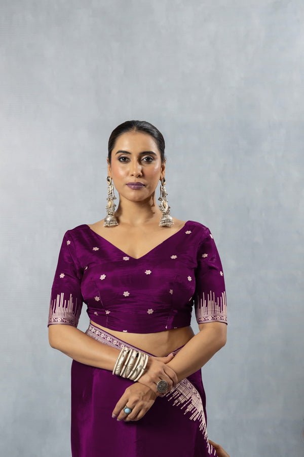 Model wearing Vanya Sarees' deep plum purple satin silk saree, showing the front view of the V-neck designer blouse with elbow-length sleeves.