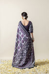 Back view of the model in a Vanya saree, displaying the full printed pattern of the pallu and the elegant hairstyle with a flower.