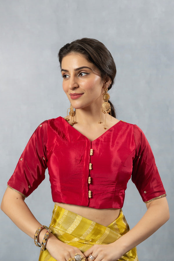 A clear front view of the Vanya Sarees readymade designer blouse in vibrant red, showing the V-neck and decorative buttons.