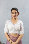 A clear front view of the readymade white designer blouse from Vanya Sarees, showing the intricate mirror work on the V-neckline.