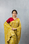 A close-up of the model holding the pallu of the Vanya Sarees yellow Banarasi saree, showcasing the rich, woven zari details.