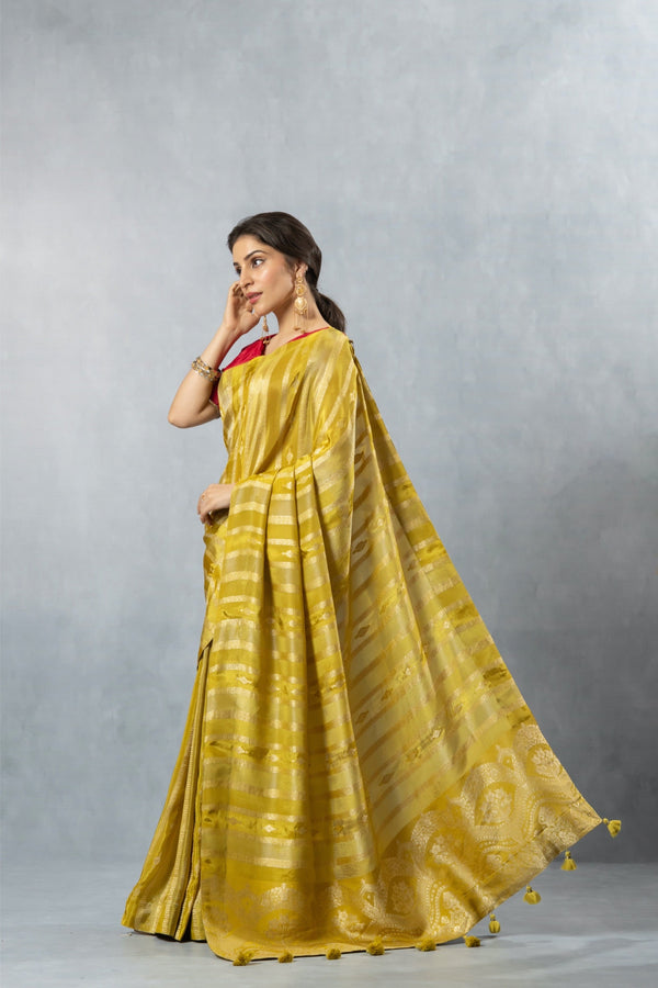 An elegant side profile of the model wearing the Vanya Sarees lime yellow striped Banarasi saree, showcasing its beautiful, fluid drape.