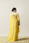 A full back view of the model in the Vanya Sarees ensemble, displaying the drape of the yellow saree and the stunning mirror work blouse.