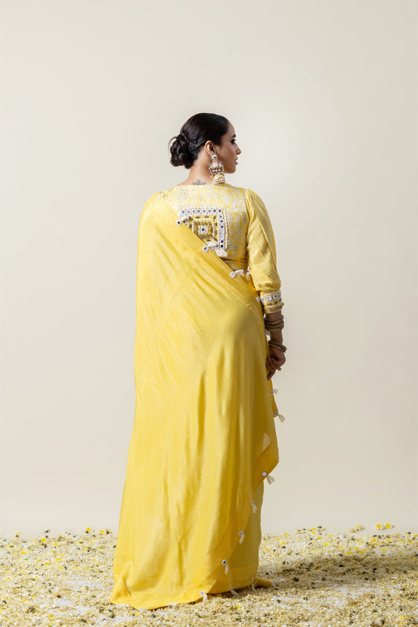 A full back view of the model in the Vanya Sarees ensemble, displaying the drape of the yellow saree and the stunning mirror work blouse.