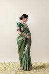 An elegant side profile of the model wearing the Vanya Sarees green Banarasi silk saree, showcasing its beautiful drape and tassels