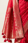 A detailed shot showing the rich, heavy gold zari weave and tassels on the pallu of the Vanya Sarees red Banarasi silk saree.