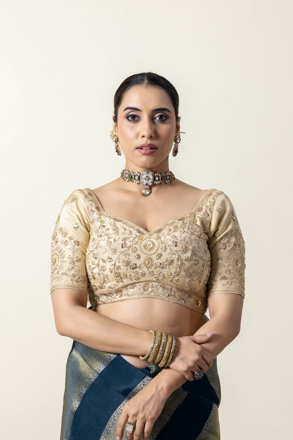 A clear front view of the Vanya Sarees heavy, hand-embroidered designer blouse in beige, featuring a sweetheart neckline and intricate zardozi work.
