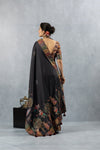 A full back view of the model displaying the magnificent, artistic folk art print on the pallu of the Vanya Sarees black silk saree.