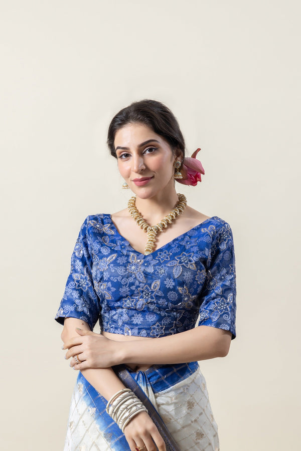 A close-up of the royal blue designer blouse from Vanya Sarees, showing the intricate floral embroidery and elegant V-neckline.