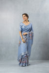 An graceful standing pose of the model in the Vanya Sarees blue floral print linen saree, perfect for a day wedding.