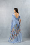 A full back view of the model in the Vanya Sarees blue linen silk saree, showcasing the large Kalamkari-style floral print on the pallu.
