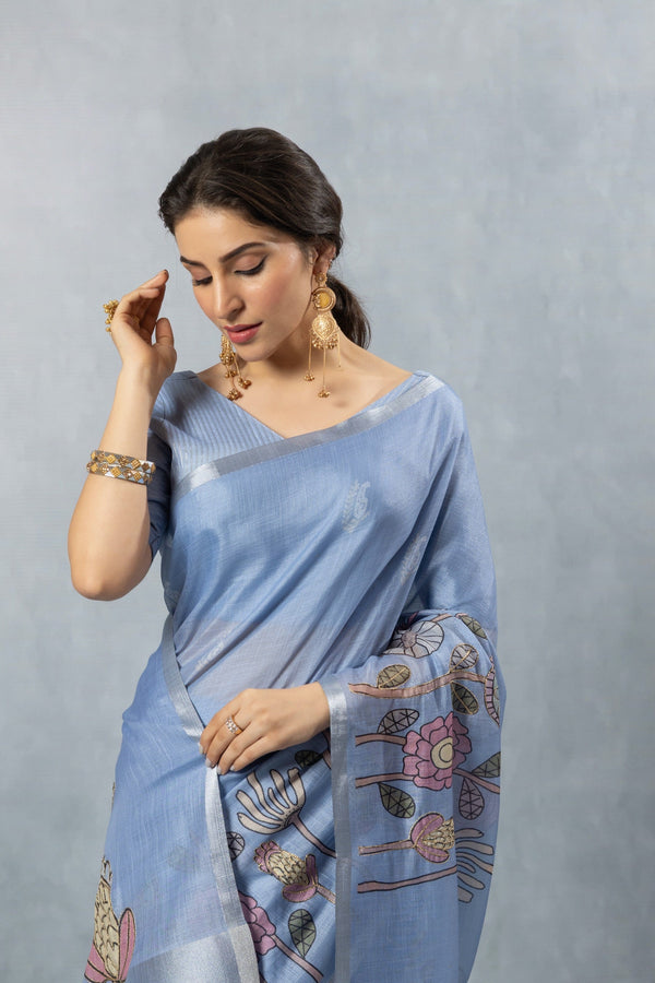 A close-up of the model in a Vanya Sarees blue linen saree, highlighting the artistic floral print with embroidery on the pallu.