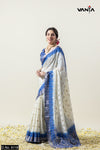 Model smiling in a full view of the Vanya Sarees white and royal blue tie-dye Chanderi silk saree with a designer blouse.