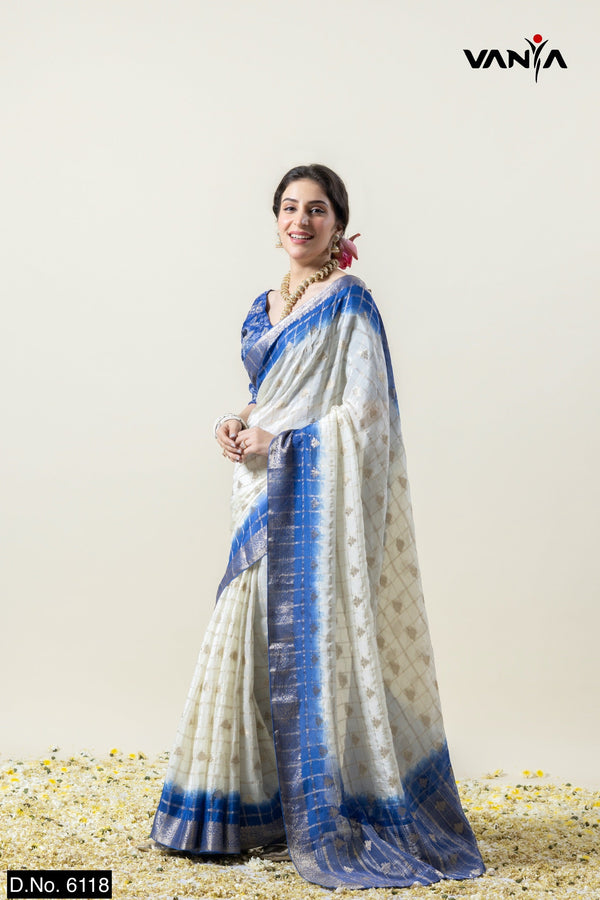 Model smiling in a full view of the Vanya Sarees white and royal blue tie-dye Chanderi silk saree with a designer blouse.