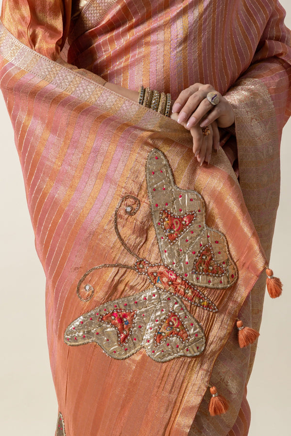 A detailed shot of the handcrafted butterfly appliqué with Zardozi and beadwork on the pallu of the Vanya Sarees peach tissue silk saree.