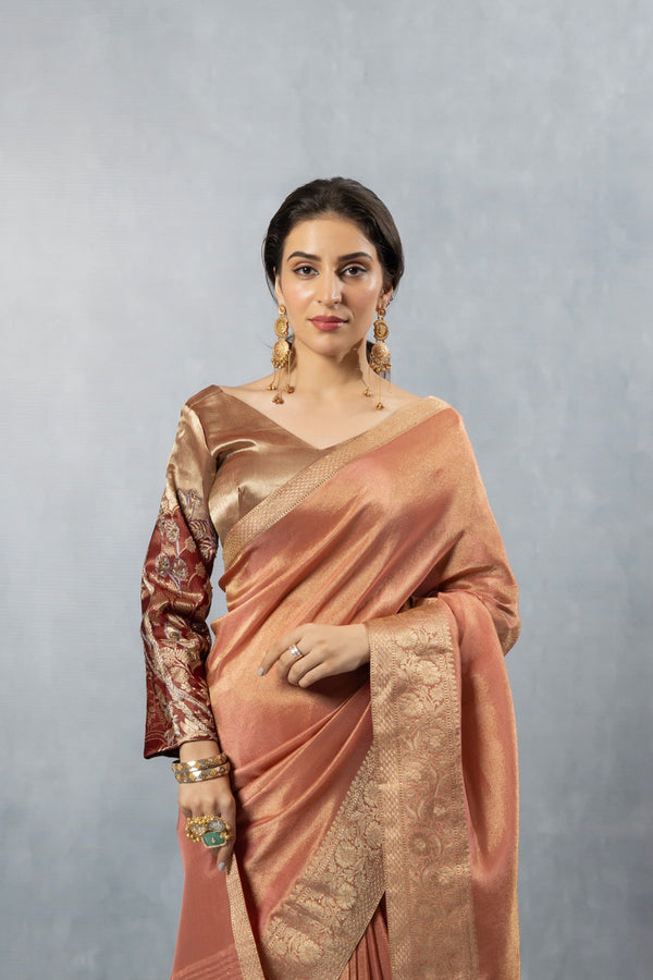 A close-up of the model in a Vanya Sarees copper silk saree, highlighting the rich Banarasi border and the brocade bell sleeve of the blouse.
