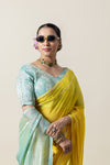A stylish close-up of a model in Vanya Sarees' yellow and green saree, highlighting the embroidered blouse and Gota Patti on the pallu.