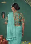 The stunning back view of the Vanya Sarees ensemble, displaying the rich Patola print of the collared blouse against the aqua blue saree.