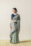 An graceful side profile of the model in the Vanya Sarees green linen silk saree, highlighting the designer blouse and pallu embellishment.