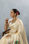 A stylish seated side profile of the model in the Vanya Sarees elephant print saree, showcasing the elegant blouse and neckline.