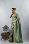 An elegant side profile of the model wearing the Vanya Sarees green and gold Banarasi silk saree, showcasing its beautiful Leheriya weave.