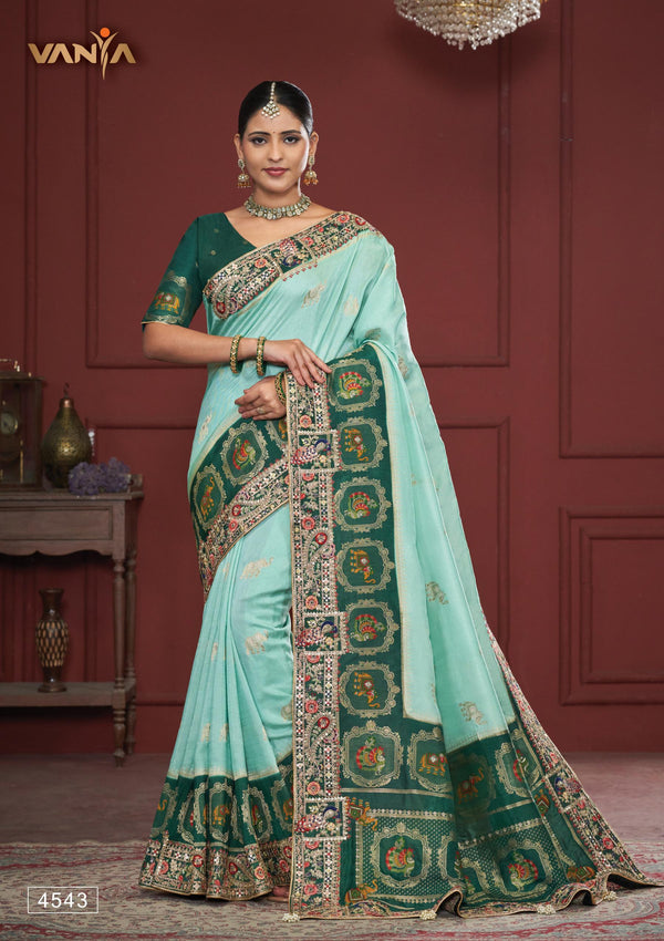 A full-length view of the model in Vanya Sarees' magnificent sea green bridal saree with a heavy, multi-color embroidered border.