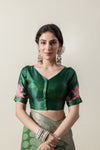 A clear front view of the Vanya Sarees readymade designer blouse in emerald green, showing the V-neck and lotus embroidered sleeve.