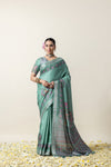 An elegant pose of the model in the Vanya Sarees sage green printed Tussar silk saree, perfect for a festive or wedding look.