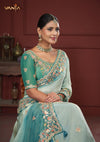 A beautiful seated portrait of the model in a Vanya Sarees green ombre saree, highlighting the rich floral and peacock embroidery.
