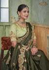 A beautiful seated portrait of the model in a Vanya Sarees green saree, highlighting the rich floral embroidery on the border and blouse.