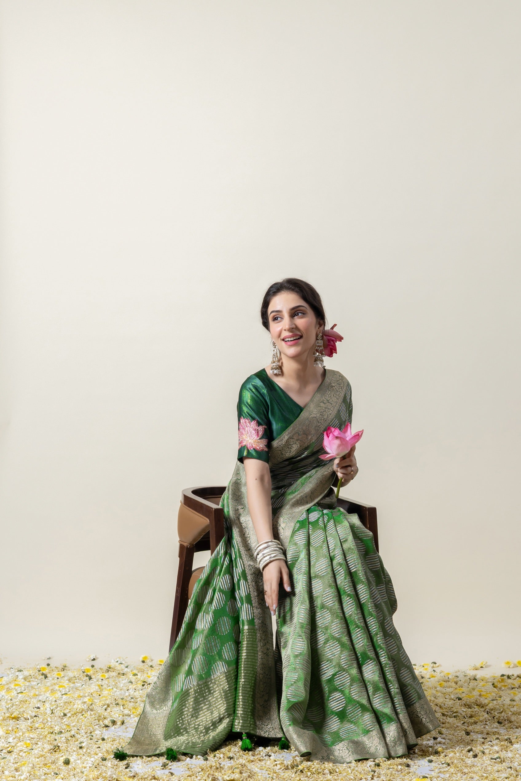 A joyful seated pose of the model in the Vanya Sarees green woven Banarasi saree, perfect for a festive occasion.