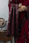 Detailed close-up of Vanya's heavy silver brocade weaving on the maroon pallu with floral motifs and black tassels.
