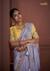 A close-up portrait of the model in a Vanya Sarees saree, highlighting the rich, multi-color floral embroidery on the lavender border.