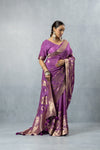 Model looking down, showcasing the full drape and antique gold zari work of the Vanya Sarees mauve purple tissue silk saree.