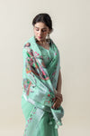 An elegant shot of the model looking down, highlighting the beautiful drape of the Vanya Sarees mint green printed linen saree.