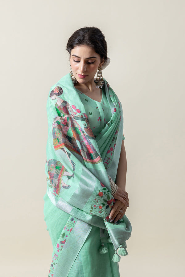 An elegant shot of the model looking down, highlighting the beautiful drape of the Vanya Sarees mint green printed linen saree.