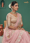 A beautiful seated portrait of the model in a Vanya Sarees pink saree, highlighting the rich mirror and thread work on the border.